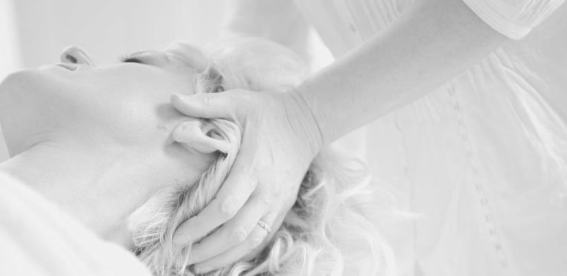 Schwarzweißaufnahme einer craniosacralen Behandlung, Hände am Kopf einer liegenden Patientin