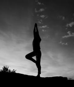 Schwarzweiße Silhouette einer Person in einer Yoga-Haltung im Gegenlicht